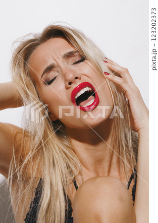 emotions and feelings concept - beautiful blonde lady in delicate lingerie, overwhelmed with passion, shouting in orgasmic bliss, her face glowing in bright light against a clean white backdrop emotions and feelings concept - beautiful blonde lady in delicate lingerie, overwhelmed with passion, shouting in orgasmic bliss, her face glowing in bright light against a clean white backdrop 123202373