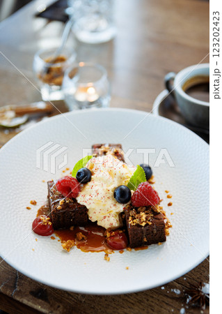 Brownie cake with salted caramel. Anglaise foam, raspberry sauce, praline nut and fresh berry. Delicious sweet dessert food closeup served for lunch in modern gourmet cuisine restaurant 123202423