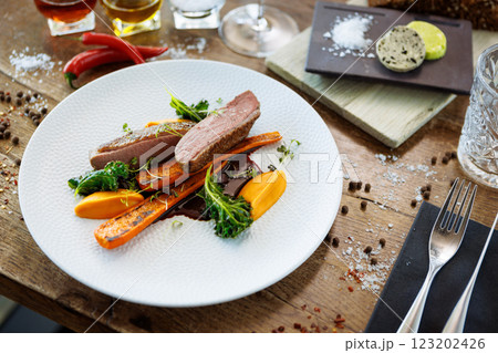 Duck fillet with sweet potato cream, roasted carrots, kale, beet-port sauce on white plate. Grilled and roasted poultry closeup served on a table for lunch in modern cuisine gourmet restaurant. 123202426