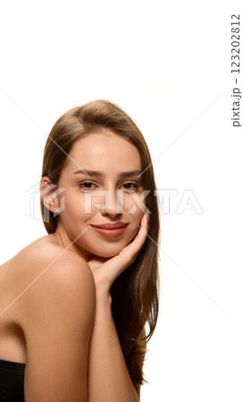 Portrait of young pretty woman with soft smile, looking at camera, resting face on hand against white studio background. 123202812