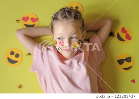 A thoughtful smiling kid surrounded by a variety of emoji icons used in social media. The problem of children using the Internet and cyberspace 123203437