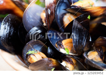 Boiled mussels in dish on dark wooden background close up Boiled mussels in dish on dark wooden background close up 123203452