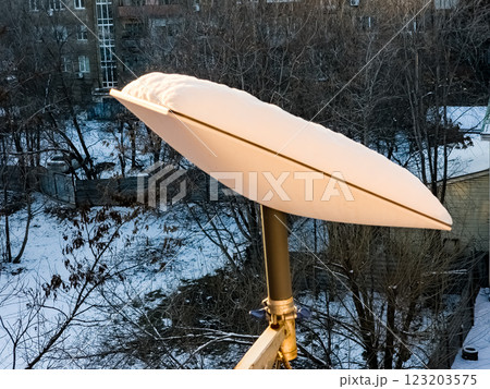 SpaceX's Starlink satellite dish is covered in snow. Starlink is disabled and does not melt snow. View from the apartment window 123203575