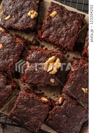 Chocolate brownie cake dessert with nuts on baking rack on dark background top view Chocolate brownie cake dessert with nuts on baking rack on dark background top view 123204202