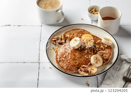 Healthy oatmeal pancakes with banana, nuts and honey on white tile background. Morning breakfast. Pancake day or Maslenitsa recipe, copy space Healthy oatmeal pancakes with banana, nuts and honey on white tile background. Morning breakfast. Pancake day or Maslenitsa recipe, copy space 123204205