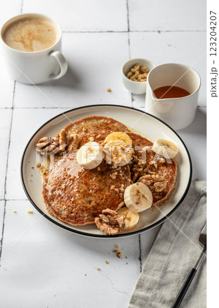 Healthy oatmeal pancakes with banana, nuts and honey on white tile background. Morning food breakfast concept. Pancake day or Maslenitsa recipe Healthy oatmeal pancakes with banana, nuts and honey on white tile background. Morning food breakfast concept. Pancake day or Maslenitsa recipe 123204207