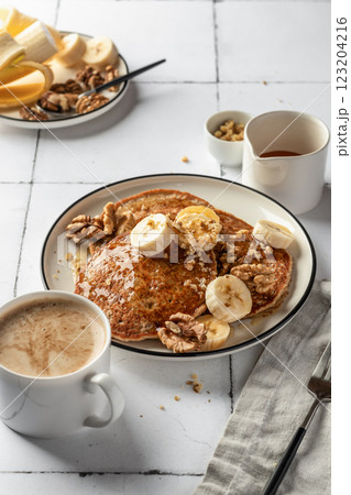 Healthy oatmeal pancakes with banana, nuts and honey on white tile background. Morning food breakfast concept. Pancake day or Maslenitsa recipe 123204216