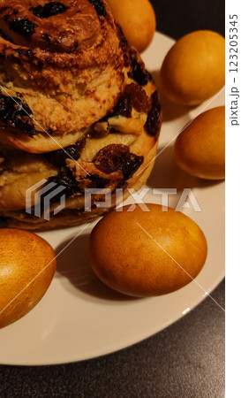Golden brown easter bread with raisins and dyed eggs creating a festive centerpiece on a white plate Golden brown easter bread with raisins and dyed eggs creating a festive centerpiece on a white plate 123205345