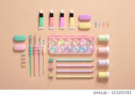 Various pastel-colored materials for creativity and art activities are neatly arranged on a beige background. Organization of the workplace. Back to school concept. 123205381