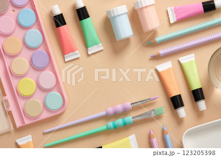 Frame with art supplies in green, yellow, pink and purple pastel colors on a beige background. Paints, colored pencils and brushes. Space for your text. Frame with art supplies in green, yellow, pink and purple pastel colors on a beige background. Paints, colored pencils and brushes. Space for your text. 123205398