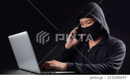 ノートパソコンを使いながら電話をかけている犯罪者。 123206047
