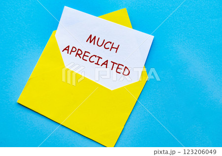 Yellow envelope on a blue cover with a white card partially pulled out with Much Appreciated text. Yellow envelope on a blue cover with a white card partially pulled out with Much Appreciated text. 123206049