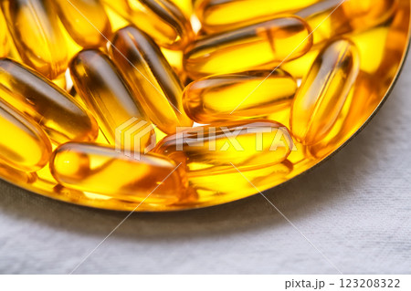 Yellow capsules with Omega-3 fish oil on a golden tray. Yellow capsules with Omega-3 fish oil on a golden tray. 123208322