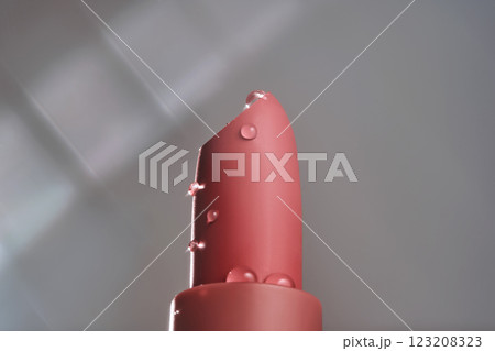 Classic lipstick with drops of water on a neutral background. Classic lipstick with drops of water on a neutral background. 123208323