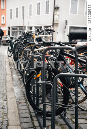 Row of urban bicycles parked in a metal bike rack along a cobblestone street. The European cityscape Row of urban bicycles parked in a metal bike rack along a cobblestone street. The European cityscape 123208958