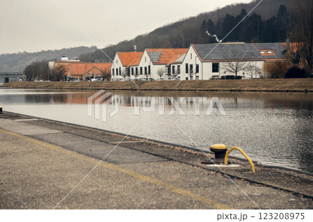 Modern white buildings with red-tiled roofs and solar panels on a riverbank. Their reflection in the Modern white buildings with red-tiled roofs and solar panels on a riverbank. Their reflection in the 123208975