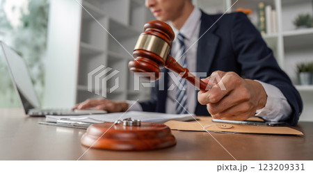 Lawyer striking gavel on desk, emphasizing decision-making during legal proceedings in modern office. 123209331