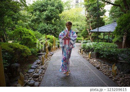 Woman in Floral Kimono Meditating in Japanese Garden  123209615