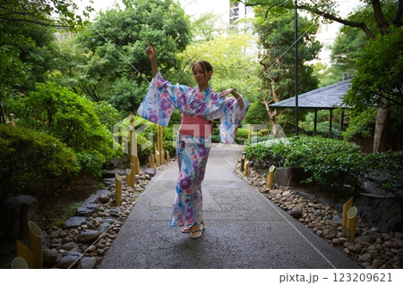 Woman Dancing in Floral Kimono in Japanese Garden  123209621