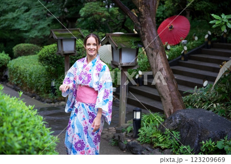 Smiling Woman in Floral Kimono Strolling in Japanese Garden  123209669