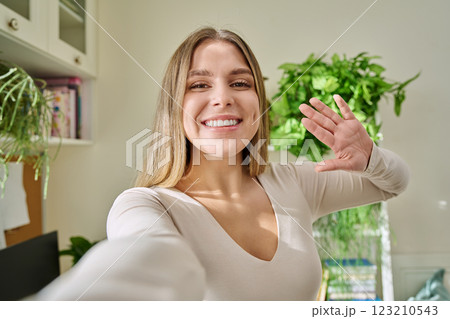 Close-up selfie portrait of young cheerful woman looking at web camera 123210543