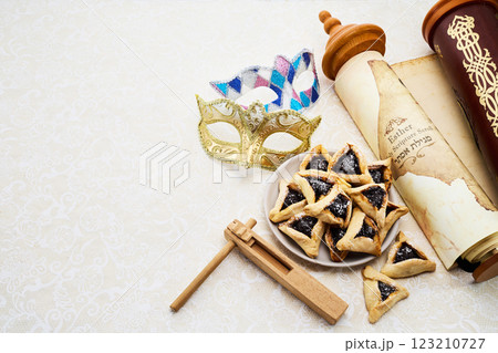 Purim Celebrations. Golden mask, scroll, gragger, and hamantaschen on decorative background 123210727