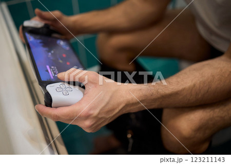 A Man Engaged in a Leisurely Activity While Relaxing in a Comfortable Bathroom Setting 123211143