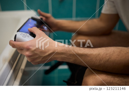 A Man Engaged in a Leisurely Activity While Relaxing in a Comfortable Bathroom Setting A Man Engaged in a Leisurely Activity While Relaxing in a Comfortable Bathroom Setting 123211146