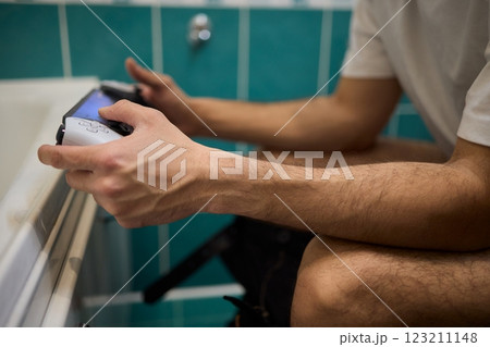 A Man Engaged in a Leisurely Activity While Relaxing in a Comfortable Bathroom Setting A Man Engaged in a Leisurely Activity While Relaxing in a Comfortable Bathroom Setting 123211148