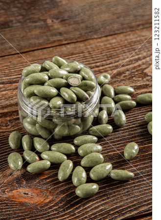 Green chocolates on a brown wooden background. Sweets in a glass jar. 123211582