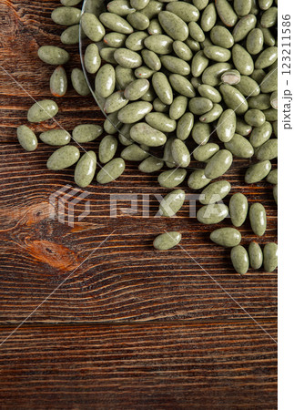 Green chocolates on a brown wooden background. Sweets in a glass plate. Filling is a nut. Green chocolates on a brown wooden background. Sweets in a glass plate. Filling is a nut. 123211586
