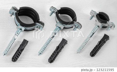 Clamp with fasteners on a white wooden background. Pipe holder. Clamp with fasteners on a white wooden background. Pipe holder. 123211595