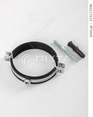 Clamp with fasteners on a white wooden background. Pipe holder. 123211596