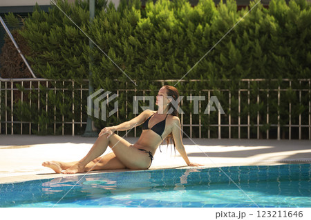 Woman Relaxing by Pool in Black Bikini Woman Relaxing by Pool in Black Bikini 123211646