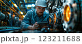 An engineer in electric blue workwear is using a tablet in a factory 123211688