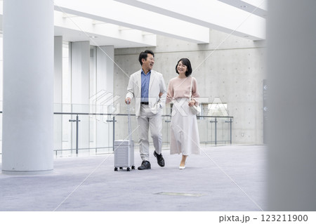 キャリーバッグを持って歩く笑顔の50代の夫婦　 123211900
