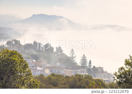 Malaga, seaside city in Andalusia, Spain, Europe. Misty mountain village, serene landscape. Houses nestled in hills, shrouded in fog. Tranquil scene. Malaga, seaside city in Andalusia, Spain, Europe. Misty mountain village, serene landscape. Houses nestled in hills, shrouded in fog. Tranquil scene. 123212070