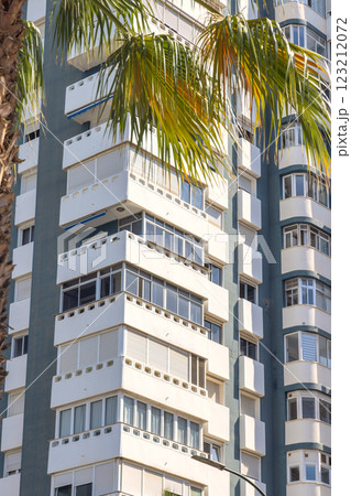 Malaga, seaside city in Andalusia, Spain, Europe. Modern apartment building with balconies and palm trees. Sunlight reflects off the white facade. Malaga, seaside city in Andalusia, Spain, Europe. Modern apartment building with balconies and palm trees. Sunlight reflects off the white facade. 123212072