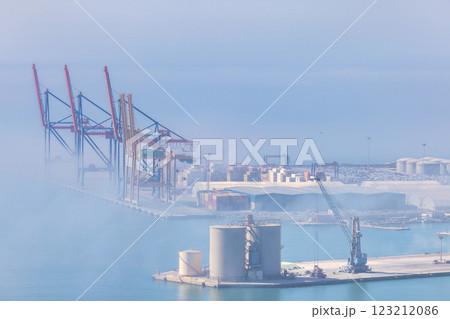 Malaga, seaside city in Andalusia, Spain, Europe. Cargo port in hazy conditions, cranes and containers visible. 123212086
