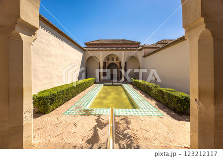 Alcazaba, palace and fortification in Malaga city at Andalusia, Spain, Europe. Serene courtyard with a reflecting pool and lush greenery, framed by elegant arches and aged walls. 123212117