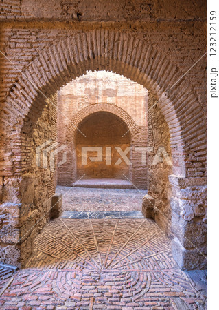 Castle of Gibralfaro in Malaga city at Andalusia, Spain, Europe. Ancient brick archways and intricate brickwork flooring lead into a dimly lit passageway. Castle of Gibralfaro in Malaga city at Andalusia, Spain, Europe. Ancient brick archways and intricate brickwork flooring lead into a dimly lit passageway. 123212159
