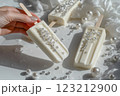 The hand holds an ice cream on a stick, decorated with edible pearls,popsicle, rhinestones. 123212900