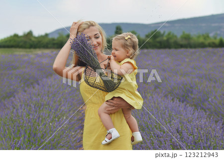 Mother and daughter in yellow dresses with basket and bouquet of lavender in lavender field in Provence Mother and daughter in yellow dresses with basket and bouquet of lavender in lavender field in Provence 123212943