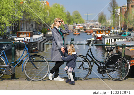 Blonde Dutchwoman mother with her daughter near the bicycle on the bridge over the water channel in Amsterdam Blonde Dutchwoman mother with her daughter near the bicycle on the bridge over the water channel in Amsterdam 123212971