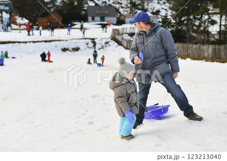 A father with child sledding in the snow A father with child sledding in the snow 123213040