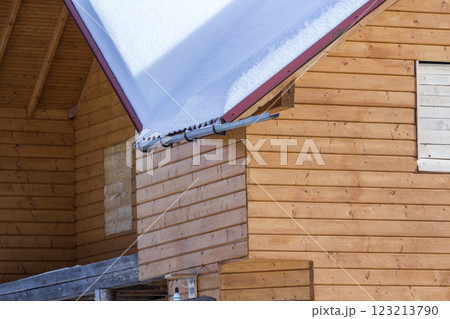 Detail of new wooden ecological traditional cottage of natural lumber materials with steep roof covered with snow on sunny winter day. Old traditions and modern professional construction concept. 123213790