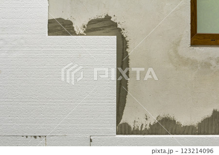Close-up detail of plastered house wall with rigid styrofoam insulation. Modern technology, construction, renovation, energy saving, alternative for mineral wool, warm comfortable house concept. Close-up detail of plastered house wall with rigid styrofoam insulation. Modern technology, construction, renovation, energy saving, alternative for mineral wool, warm comfortable house concept. 123214096