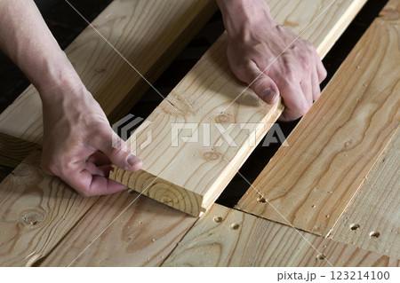 Close up of strong muscular hands of professional carpenter installing natural wooden new planks on wooden frame floor Reconstruction, improvement, renovation and carpentry concept. Close up of strong muscular hands of professional carpenter installing natural wooden new planks on wooden frame floor Reconstruction, improvement, renovation and carpentry concept. 123214100