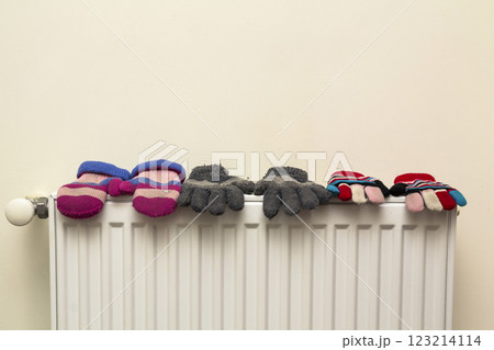 Children's warm hand knitted striped woolen gloves drying on hea Children's warm hand knitted striped woolen gloves drying on hea 123214114