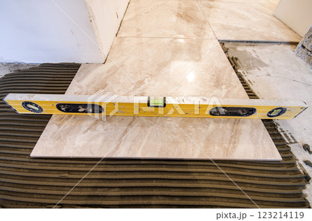 Ceramic tiles and tools for tiler. Floor tiles installation. Home improvement, renovation - ceramic tile floor adhesive, mortar, level Ceramic tiles and tools for tiler. Floor tiles installation. Home improvement, renovation - ceramic tile floor adhesive, mortar, level 123214119